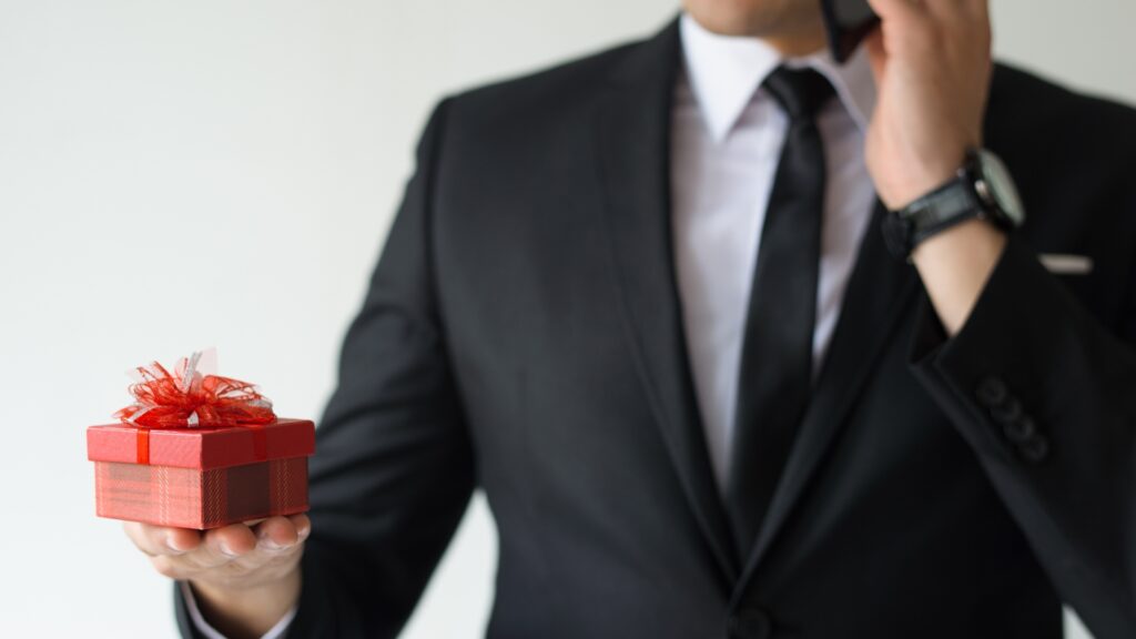 A man in a suit holds a red gift box