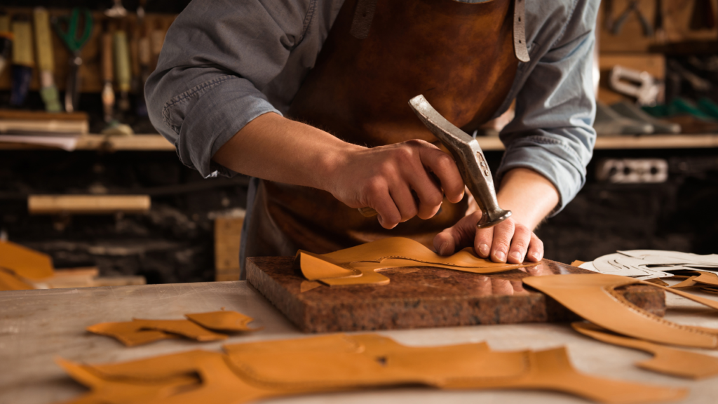 A man carefully works on a piece of leather.