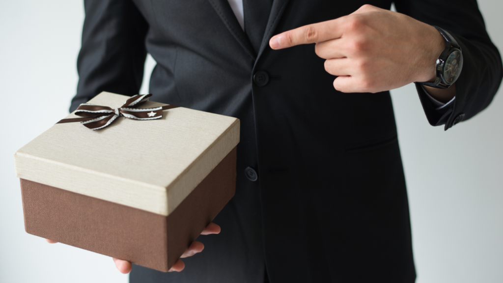 A man in a suit holds a wrapped gift box.