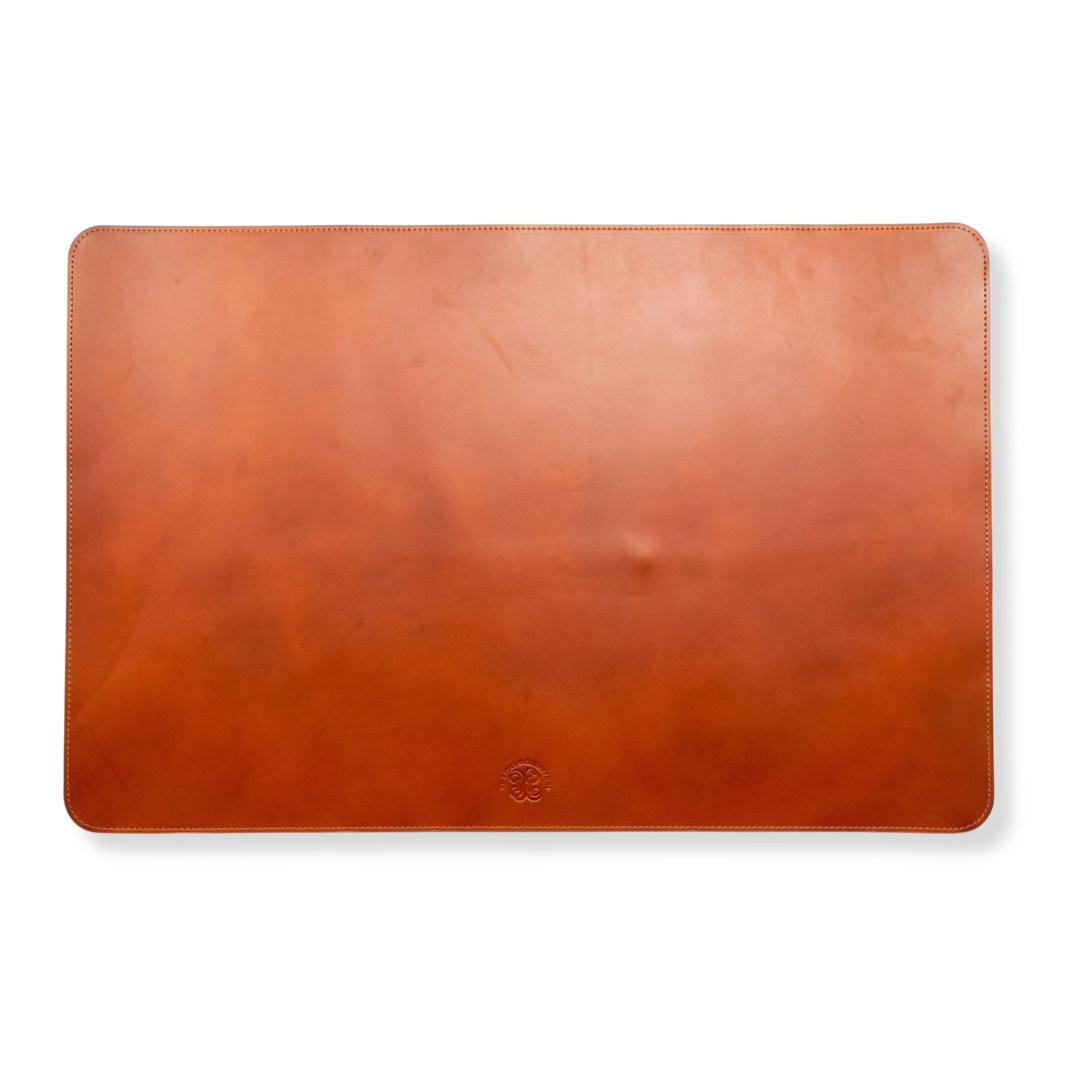 A smooth brown leather desk mat with rounded corners and visible stitching