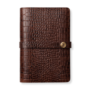 Medium brown crocodile-embossed leather notebook cover by The Leather Collection, secured with a leather strap and round logo button.